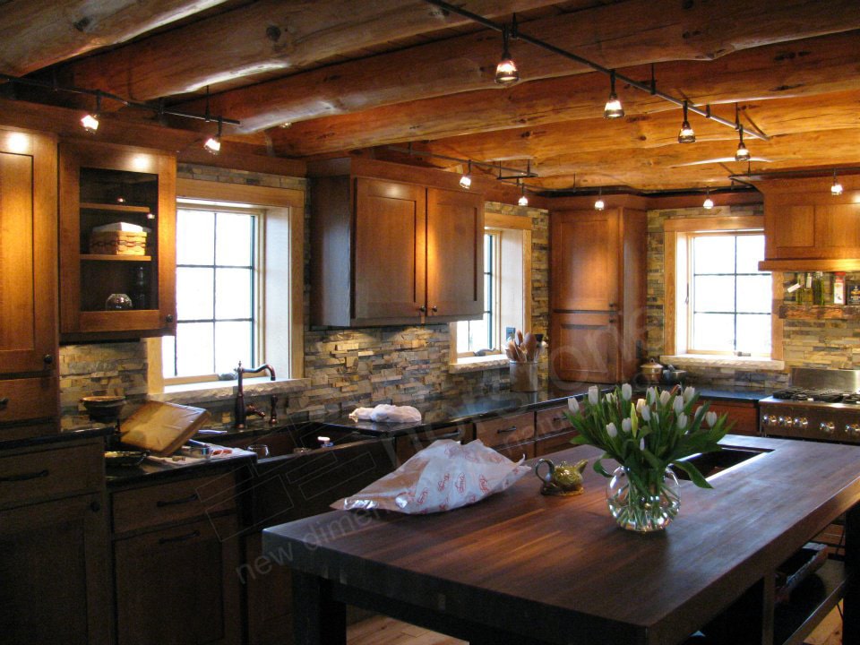 Norstone Ochre Blend Rock Panels used on a modern rustic kitchen backsplash with a large island and exposed natural log ceiling beams